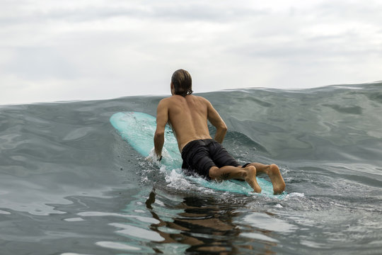 Indonesia, Java, man lying on surfboard on the sea