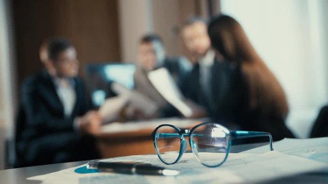 financial chart near dollars seen by unfocused glasses ( colleagues meeting to discuss their future financial 

plans only silhouettes being viewed )
