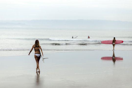 Woman carrying surfboard at the sea