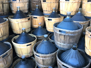 wine carboys bottles enclosed in wickerwork outside at farm