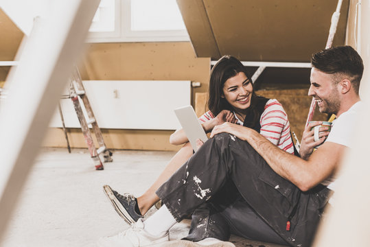 Young couple on construction site of their new home, using digital tablet