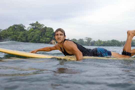 Indonesia, Java, man lying on surfboard on the sea