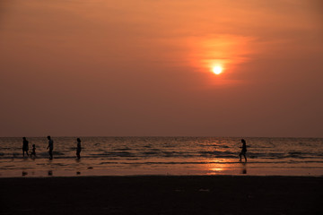 silhouette people playing on beach in the sea on sunset background