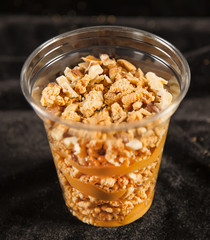 Tasty peanut cake in plastic cup on black bacground