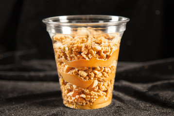 Peanut cake in plastic cup on black bacground