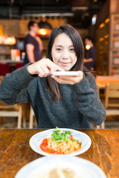 Woman taking photo on her dishes in restaurant