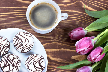 Романтический завтрак с кофе,пирожным и тюльпанами на деревянном фоне.