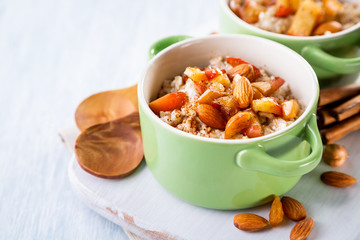 Tasty oat porridge with caramelized apples and almonds on a napkin