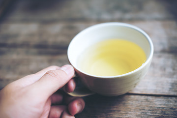 Hand holding clay tea mug on vintage wooden table