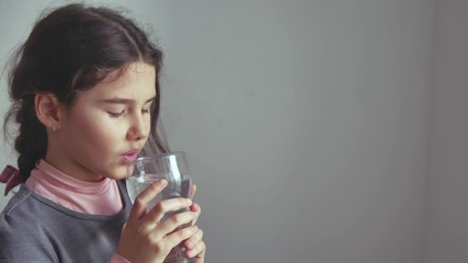 teen girl drinks water from a glass cup the indoor