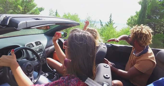 Young friends enjoying coastal scenery while riding in convertible