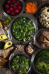 Vegetables, chickpeas, herbs in bowls in the water, half an avocado on the table