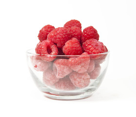 Red raspberries in a glass bowl on a white background