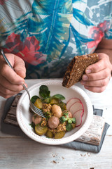 Man eats a salad with potatoes and mustard