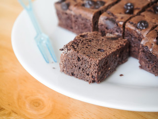 Brownies chocolate cake with plastic fork on white dish