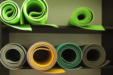 Few rolls of mat for yoga, pilates and fitness on the shelf at the gym,  horizontal image