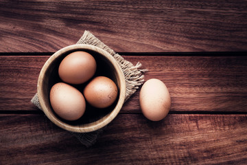 Still life with eggs in bowl on brown wooden background