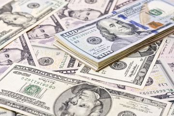 A stack of one hundred dollar bills on a background of dollars 