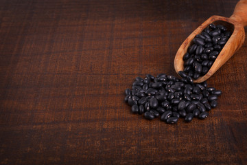 Black beans in scoop on wooden background