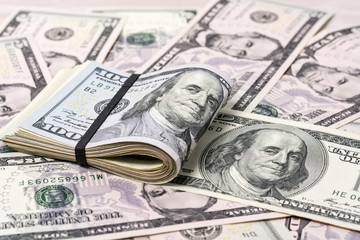 A stack of one hundred dollar bills on a background of dollars 