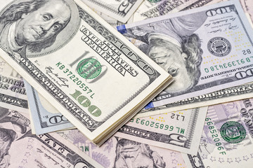 A stack of one hundred dollar bills on a background of dollars 
