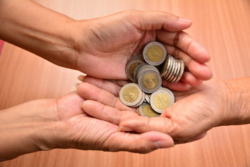 Person putting coin in anothen hand of person for saving and business concept.