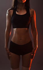 Fototapeta na wymiar Sports woman in black top and shorts on a gray background.