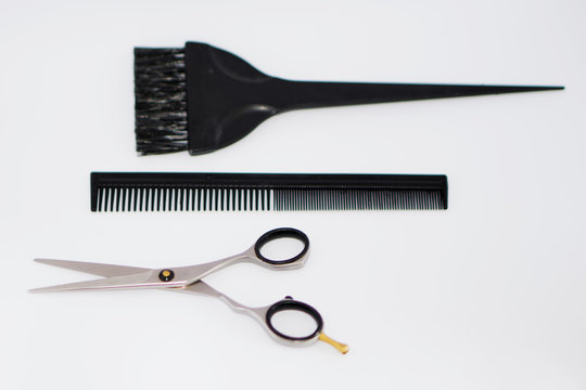 Hairdressing tools, metal scissors stainless steel, plastic comb and brush painting in defokus. White backgraund, nobody.