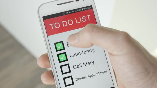 Using a To Do list  app on a smartphone. Checking the tasks one by one.