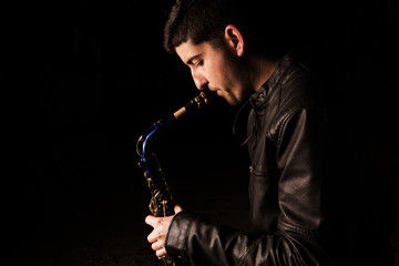 Naklejka premium Man playing saxophone, with black background