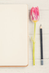 Open notebook, pencil and tulip
