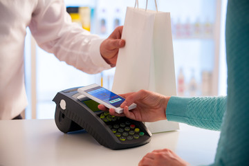 Wireless payment using smartphone and NFC technology. Close up. Customer paying with smart phone in...