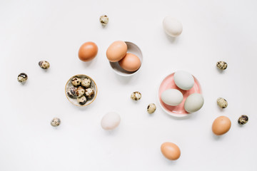 White and brown Easter eggs and quail eggs on white background. Flat lay, top view. Traditional spring concept.