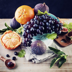 Season Fruit Background with Mandarin, Blue Grape and Figs in Viintage Bowl on Wooden Board