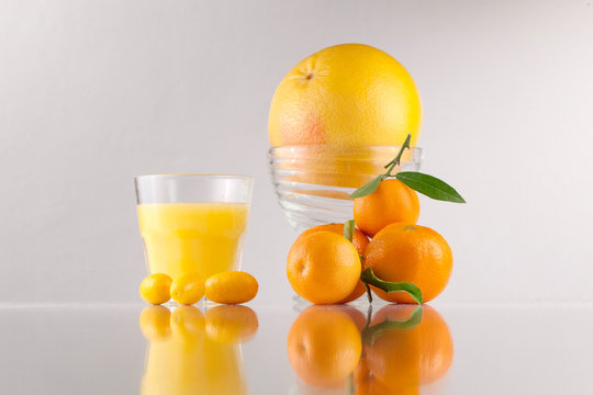 Composition of oranges, orange juice in low glass and glass bowl