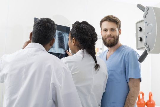 Male Radiologist With Colleagues Examining X-ray In Hospital