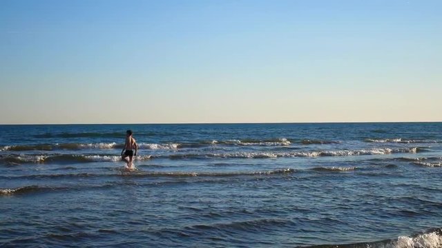 Young caucasian man slowly entering the cold sea