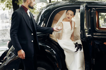 elegant handsome stylish groom helping gently gorgeous bride, holding hand. unusual luxury wedding...