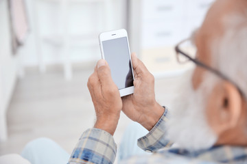 Senior man sitting with smart phone, closeup