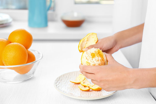 Female hands peeling orange, closeup