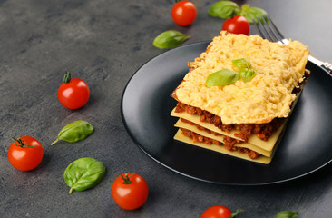 Plate with golden lasagna on gray background