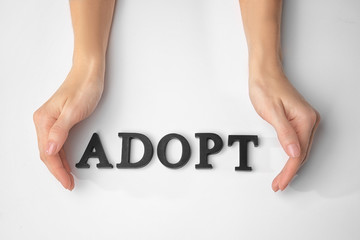 Female hands and word ADOPT on white background