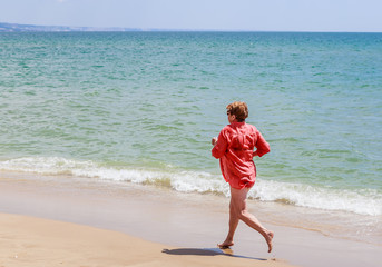 Fototapeta na wymiar Woman runs along the seashore