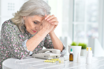 Sick elderly woman with medicines