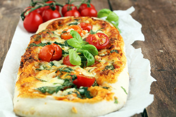 Hot pizza slice with melting cheese on a rustic wooden table.