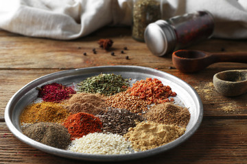 Metal plate with aromatic spices on wooden table