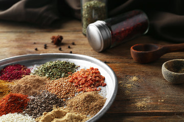 Metal plate with aromatic spices on wooden table