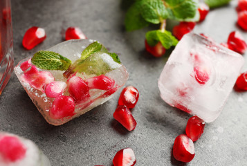 Ice with pomegranate seeds on gray background, closeup