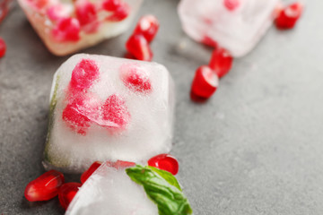 Ice with pomegranate seeds on gray background, closeup