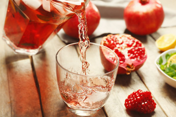 Pouring cold fruit cocktail into glass on wooden table, closeup